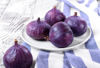 Ripe figs on ceramic plate on the white wooden table