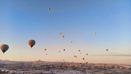 Colorful hot air balloons flying over the valley with fairy chimneys in winter season. Lots of Hot air balloons at the sunrise sky landscape in Cappadocia, Turkey