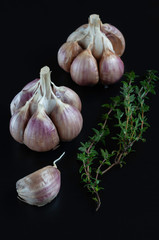 Garlic wedges and thyme sprig on a dark background.