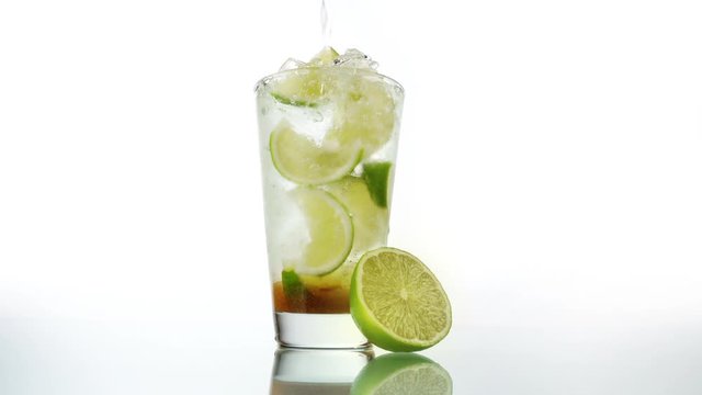 Pouring Cachaca in a Caipirinha Cocktail on white Background - Lime and brown Sugar
