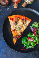 slice pizza and salad leaves in a plate on the table (tasty snack) menu concept background. top view. copy space for text
