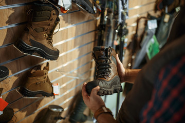 Man choosing boots for hunters in gun shop