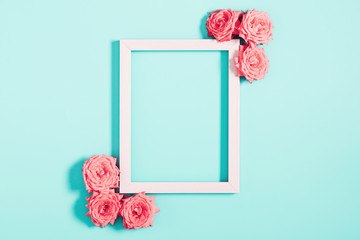 Beautiful flowers composition. Blank frame for text, pink rose flowers on pastel blue background. Womens day, mothers day, concept, design. Flat lay, top view, copy space