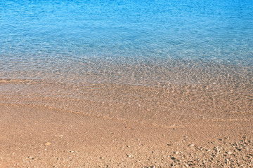 Fototapeta na wymiar Waves with foam blue sea on a sunny sandy beach in resort on summer vacation rest.