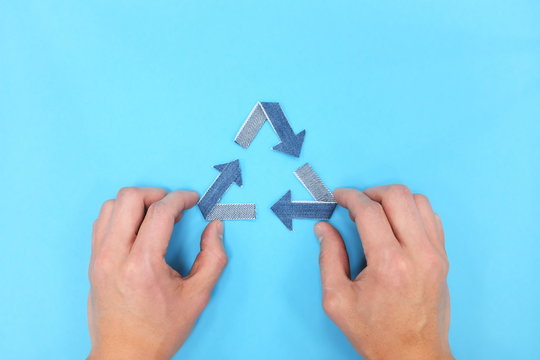 Recycling symbol made of denim jeans flat lay. Blue background with copy space.