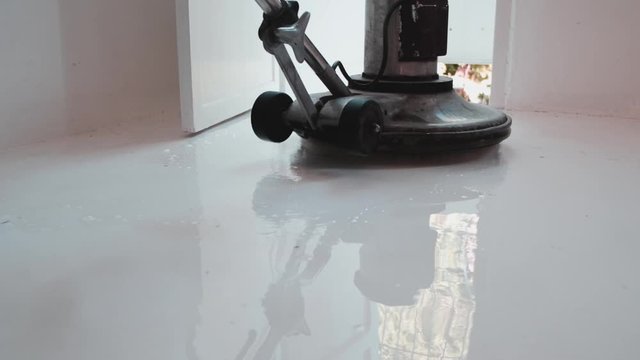 Close up of the floor scrubber, cleaning and polishing the white floor, maintenance the white photo studio floor, effective professional cleaning, the concept of business cleaning and care service.