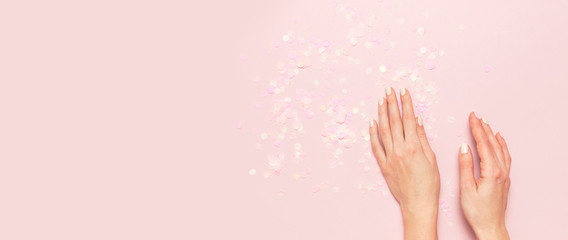 Stylish fashionable female manicure in pastel colors. Hands of young girl on pink background with...