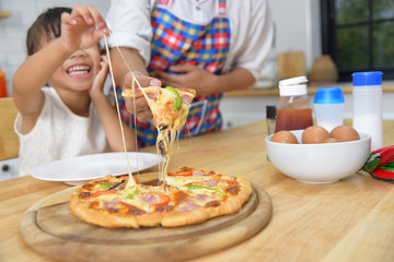 Asian mother and child eat pizza