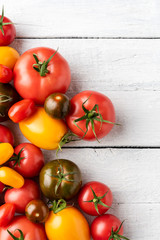 Mix of tomatoes on white wooden background with copyspace. Top view