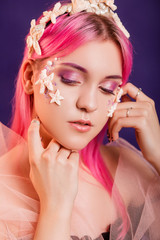 Close up portrait of a young beautiful girl with pink hair and professional make-up, sea princess with starfish and shells on her face and head. Halloween makeup.