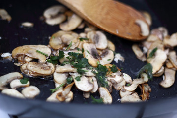 Adding parsley into fried champignon mushroom