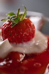 Cream dessert with fresh strawberries and strawberry jam in a glass bowl on a dark background