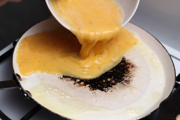 Pouring beaten eggs into frying pan. Making omelette series.