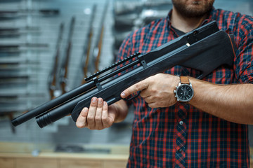 Male person with pneumatic rifle in gun shop