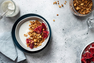 Greek yogurt with granola and red orange in a bowl on a gray background. detox meal for health nutrition. horizontal image, place for text, flat lay.