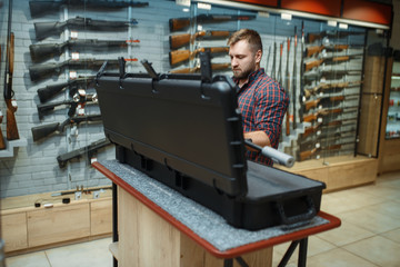 Man takes sniper rifle from the case in gun shop