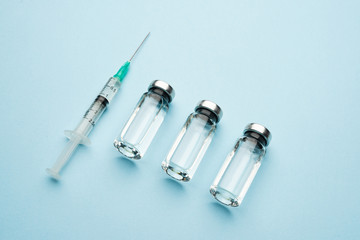 A row of medical vials. Glass bottles with a transparent medicine and a syringe.