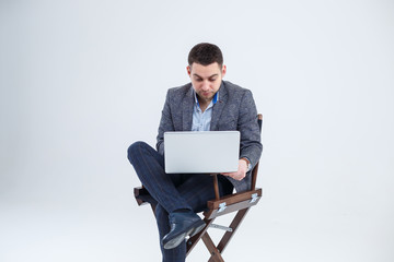 Male teacher director businessman sitting on a chair studying documents. He is looking at the laptop screen. New business project.