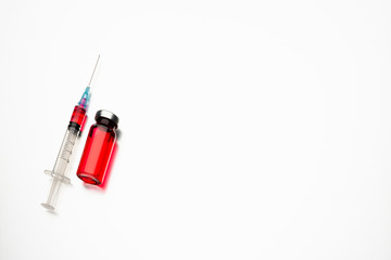 Medical vial and syringe on a light background. Red medicine in a bottle.