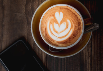 Top down image of a Latte and mobile phone showing the coffee culture or weekend lifestyle of millennials