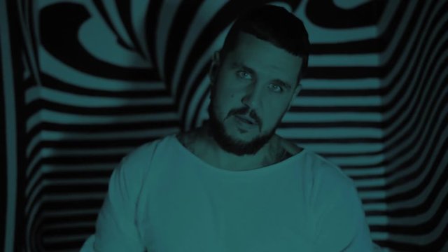 Crazy man in a straitjacket in a psychedelic room looks at you