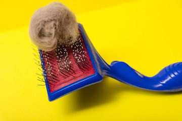 Comb for animal hair and gray wool on a yellow background. Animal hairbrush.