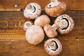 Horizotal photo of pile of small fresh organic mushrooms champignons on wooden board table. Stuffed mushrooms, covered in herbs. Ingredients with fresh mushrooms on wooden background