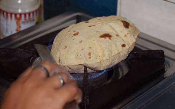 Preparing Indian puffed roti or chapati (Wheat bread)
