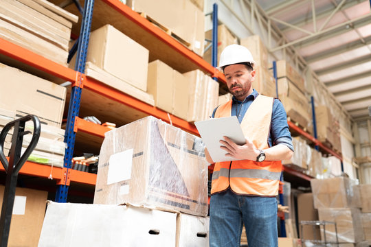 Male Worker In Protective Workwear Standing At Warehouse
