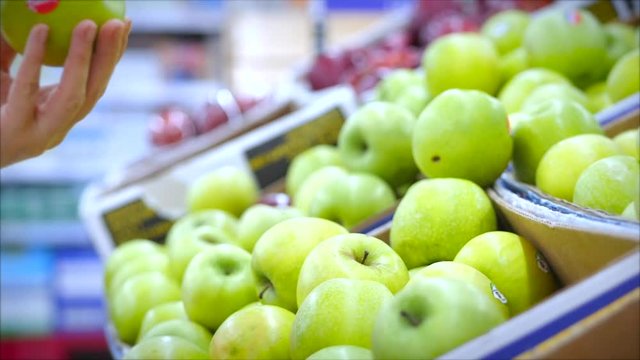 Woman makes purchases in a supermarket, a female hand picks an apple in a market, a supermarket.