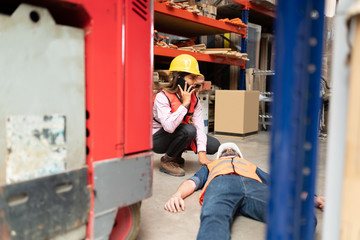 Fototapeta na wymiar Young Employee Helping Fainted Coworker By Forklift
