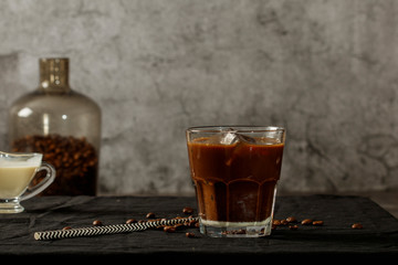 Iced coffee with milk on a dark background. Coffee with ice and cream on a gray background close-up.