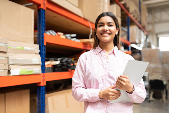 Young Latin woman working in a warehouse and doing some inventory