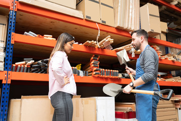 Attractive Salesman Standing With Tools By Woman At Store