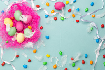 Easter colored eggs in a pink nest on blue background.