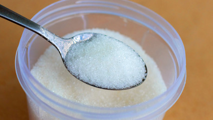 Teaspoon with sugar on a background of cups with sugar. Sugar for tea_