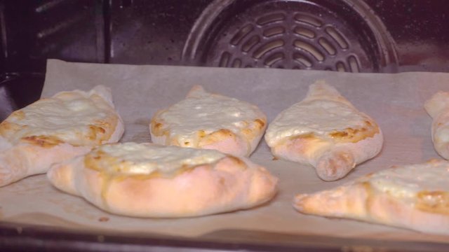 Georgian khachapuri megruli with cheese. Someone takes a piece of khachapuri from a plate. Slow motion. 4k