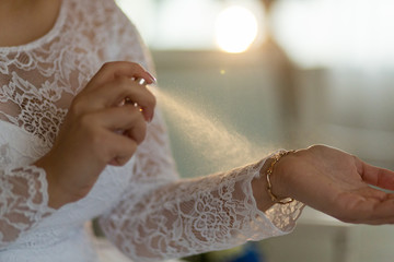 The bride uses perfume on her wedding day