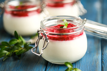 Classic italian dessert creamy panna cotta with cherry sauce on a blue rustic background copy space.