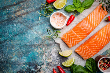 Raw salmon fillet and ingredients for cooking, seasonings and herbs on a blue background . Top view