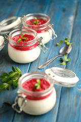 Classic italian dessert creamy panna cotta with cherry sauce on a blue rustic background copy space.