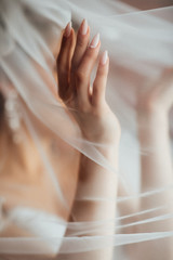Bride's hand under the veil. Beautiful manicure. Fashion, beauty, style. Morning of the bride.