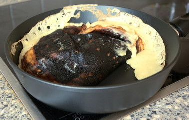 Cooking fail. Burned omelet in pan close-up. Amateur culinary. Chores.