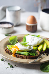 Healthy breakfast whole wheat toasted bread with avocado and poached egg over white background