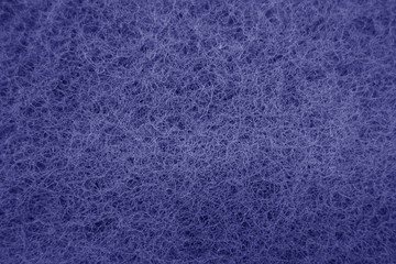 Cleaning sponge rubbing surface close up with blue effect in blue tone.