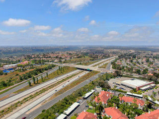 Fototapeta premium Aerial view of highway surrounded by villa in suburb. Intersection city transport road with vehicle movement. California, USA.