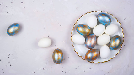 Colored Easter eggs in blue and gold lie on gray background. Minimalistic holiday layout. Top view.