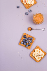 Sandwiches with peanut butter and fruits and seeds on a gray background. Healthy vegetarian breakfast. Top view, flat lay, copy space.