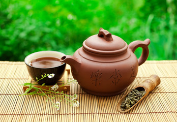 Chinese tea ceremony in the garden with dry green tea in scoop on a wooden table.