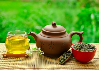 Chinese tea ceremony in the garden with dry green tea in scoop on a wooden table.